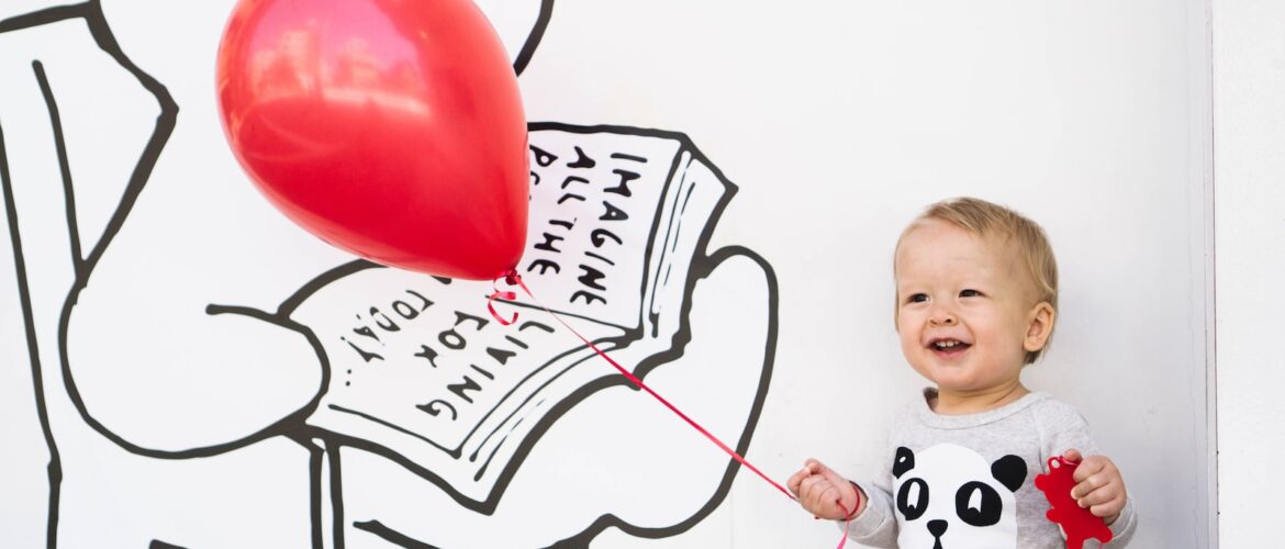 smiling toddler holding red balloon