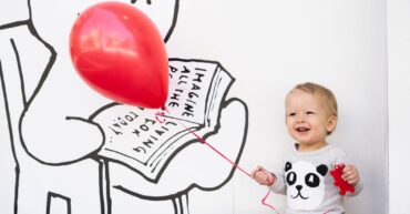 smiling toddler holding red balloon
