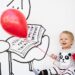 smiling toddler holding red balloon